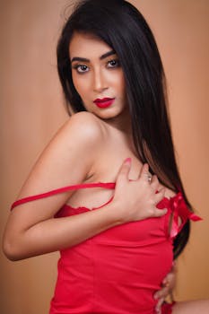 Sensual portrait of an adult woman posing in red lingerie with alluring red lips.