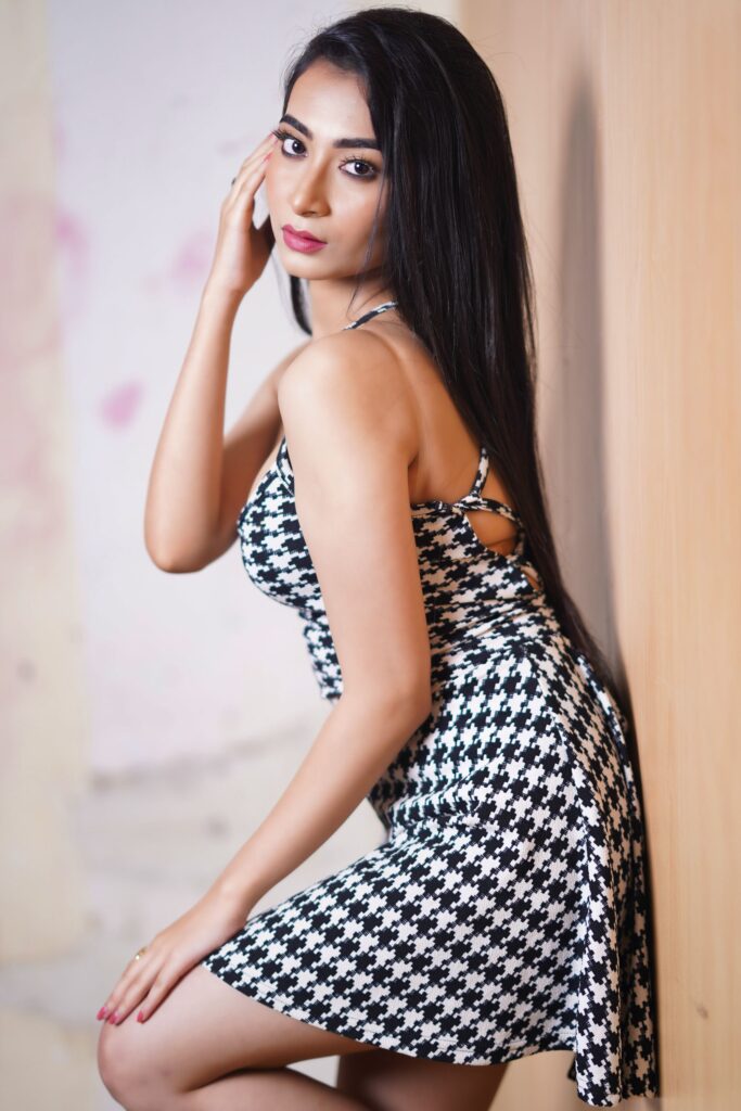 Elegant portrait of a woman posing in a black and white dress indoors.